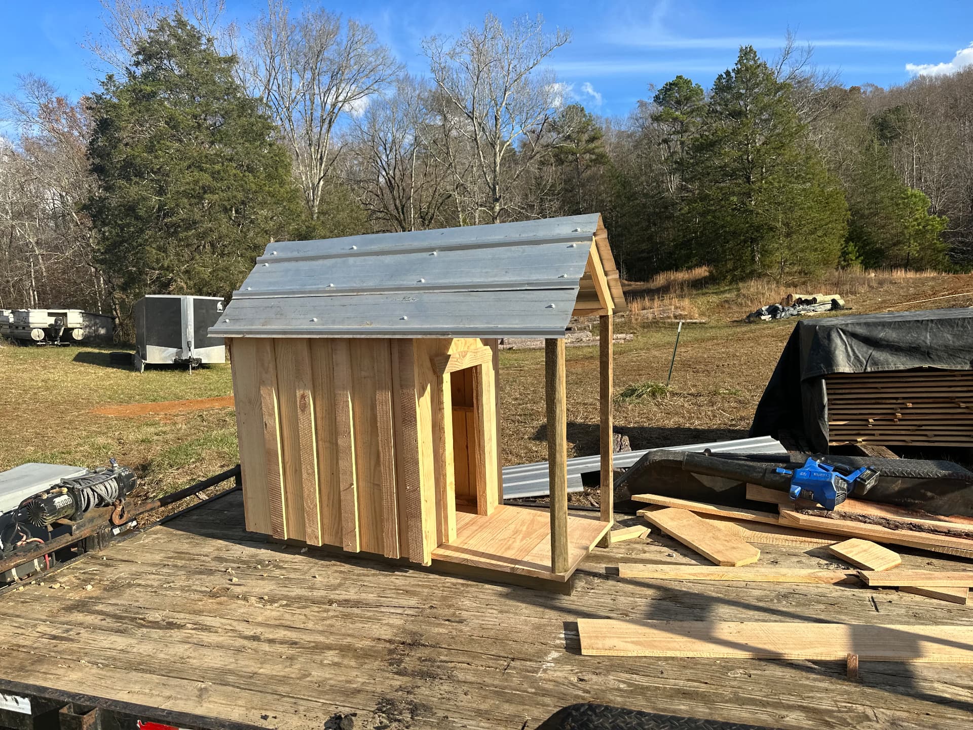 Custom-built cedar dog house with porch and metal roof